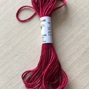 May include: A spool of red embroidery floss with a white label that reads "SOIE 2936 A".