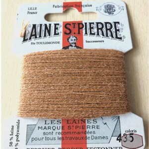 May include: A spool of brown embroidery floss labeled "LAINE STPIERRE" with the text "LES LAINES MARQUE STPIERRE sont recommandées pour tous les travaux de Dames REPRISER BRODER FESTONNER" and the color number "435".