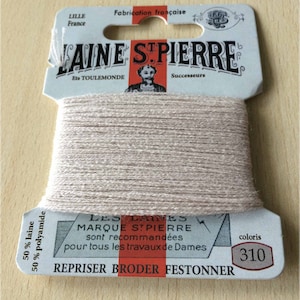 May include: A spool of beige embroidery thread labelled "LAINE STPIERRE" with the text "LES LAINES MARQUE STPIERRE sont recommandées pour tous les travaux de Dames REPRISER BRODER FESTONNER" and "coloris 310".