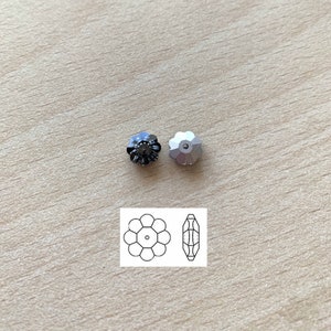 May include: Two flower-shaped rhinestones, one black and one silver, with a diagram of the rhinestone shape and a single facet.