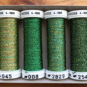 Puede incluir: Primer plano de seis carretes de hilo metálico en una variedad de colores verdes y negros. Los carretes están etiquetados con los números: 3625, 045, 008, 2829, 2540 y 050.