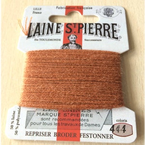 May include: A spool of brown embroidery floss with a white label that reads "LAINE STPIERRE" and "LES BAINS MARQUE STPIERRE sont recommandees pour tous les travaux de Dames REPRISER BRODER FESTONNER" with a color code of "4.4".