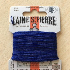 May include: A spool of dark blue Laine St. Pierre thread, with the number 655 on the label. The label also includes the text "Fabrication française" and "REPRISER BRODER FESTONNER". The thread is 50% wool and 50% polyamide.