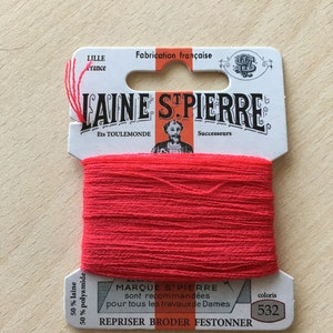 May include: A spool of bright red Laine St. Pierre embroidery thread. The label reads "Fabrication française" and includes the text "REPRISER BRODER FESTONNER" and the color code 532. The thread is 50% wool and 50% polyamide.