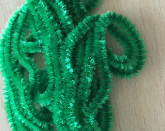 May include: A pile of green pipe cleaners, also known as chenille stems, are twisted and curled together.