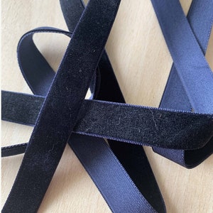 Peut inclure: Deux rubans en velours bleu marine avec une fermeture à crochets et boucles. Les rubans sont croisés l'un sur l'autre.