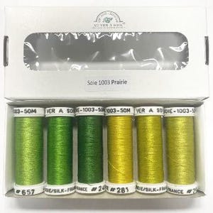 Puede incluir: Seis carretes de hilo de bordar verde y amarillo, etiquetados "Sole 1003 Prairie" y "VER A SOBIE-1003-50M".