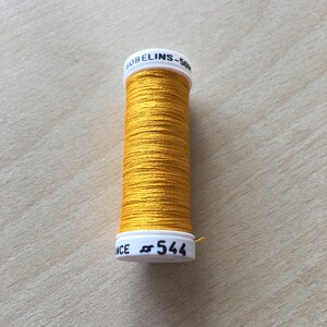 May include: A spool of yellow embroidery floss with a white label that reads "GOBELINS - 50m" and "# 544".