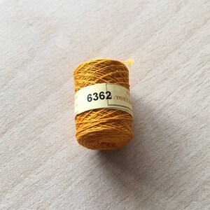 Può includere: Un'bobina di filo giallo brillante con un'etichetta che recita "6362".