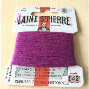 May include: A magenta yarn spool from Laine St. Pierre, with the text "LILLE France" and "Fabrication française". The label reads "REPRISER BRODER FESTONNER" and "coloris 542". The yarn is 50% wool and 50% polyamide.