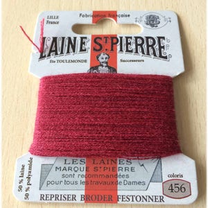 May include: A spool of red Laine St. Pierre thread, with the text "Laine St. Pierre" and "Fabrication française". The label also includes the text "coloris 456" and "50% laine 50% polyamide".