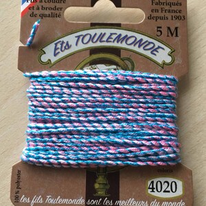 May include: A spool of pink and blue embroidery thread with the text "Ets Toulemonde" and "les fils Toulemonde sont les meilleurs du monde" on the label. The label also states "Fabriqués en France depuis 1903" and "5 M".
