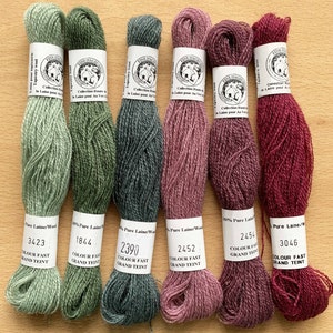 May include: Six skeins of wool yarn in various shades of green, pink, and red. The yarn is labelled with the brand name "Fine Paille" and the colour numbers 3423, 1844, 2390, 2452, 2454, and 3046. The yarn is described as "100% Pure Laine/Wood" and "Colour Fast Grand Teint".
