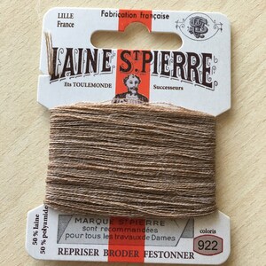 Könnte beinhalten: Eine Spule braunen Laine St. Pierre-Garns, mit dem Text "LILLE France" und "Fabrication française" auf dem Etikett. Das Etikett enthält auch den Text "REPRISER BRODER FESTONNER" und die Nummer "922".