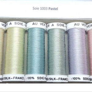 May include: Six spools of 100% silk thread in pastel colors. The spools are labeled "Soie 1003 Pastel" and "AU VER A SOIE".