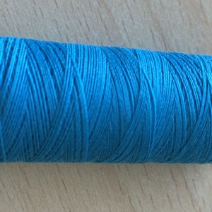 May include: A spool of turquoise blue thread labeled "100% Polyester" and "C.A.C. 40/2"