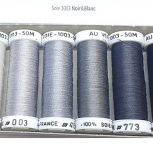May include: A pack of 10 spools of silk thread in shades of gray and black. The spools are labeled "Soie 1003 Noir&Blanc" and "pack soie 10".