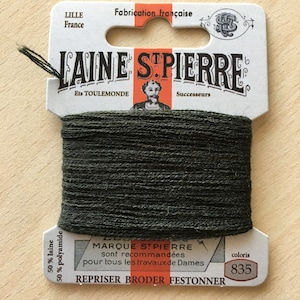 May include: A spool of dark green embroidery thread labeled "Laine St. Pierre" with the text "50% laine 50% polyamide" and "coloris 835".