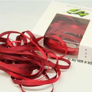 May include: A spool of deep red silk ribbon, with the brand name "Au Ver a Soie" printed on the box.