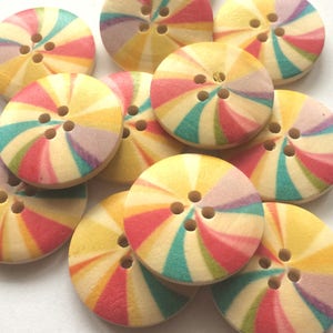 May include: A collection of colourful wooden buttons with a swirl pattern. The buttons are yellow, pink, red, green, and blue. Each button has five holes.