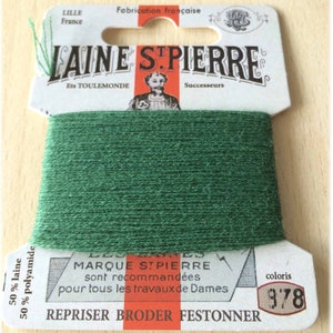 May include: A spool of green embroidery floss with a white label that reads "Laine St. Pierre Ets Toulemonde Successeurs" and "Marque St. Pierre sont recommandees pour tous les travaux de Dames Repriser Broder Festonner" with the color number "978".
