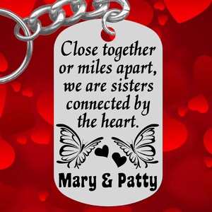 May include: Silver keychain with a tag that reads "Close together or miles apart, we are sisters connected by the heart. Mary & Patty". The tag features two black butterflies with hearts between them.