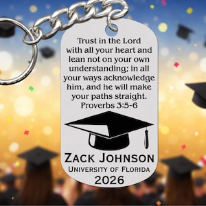 May include: A silver-colored graduation keychain with a ring and chain. The keychain has a rectangular tag with the text "Trust in the Lord... Proverbs 3:5-6". It also includes a graduation cap graphic, the name "ZACK JOHNSON", "UNIVERSITY OF FLORIDA", and the year "2026".