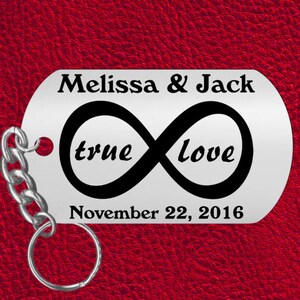 May include: Silver keychain with a black infinity symbol and the words "true love" inscribed. The keychain also has the names "Melissa & Jack" and the date "November 22, 2016" engraved on it.