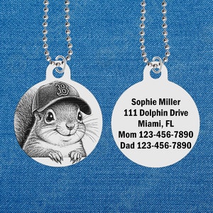 May include: A silver round tag with a black and white image of a squirrel wearing a baseball cap with the number 38 on it. The back of the tag has the text "Sophie Miller 111 Dolphin Drive Miami, FL Mom 123-456-7890 Dad 123-456-7890".