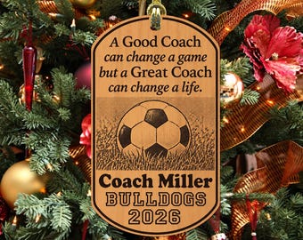 May include: A rectangular wooden ornament with rounded corners, featuring a gold hanging cord. The text reads: A Good Coach can change a game but a Great Coach can change a life. Coach Miller BULLDOGS 2026. A soccer ball graphic is centered.