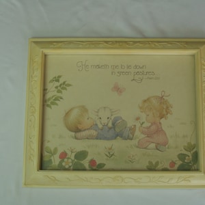 May include: A framed print with a yellow frame and a white mat. The print features a watercolor illustration of two children with a lamb. The text on the print reads "He maketh me to lie down in green pastures." - Psalm 23:2.