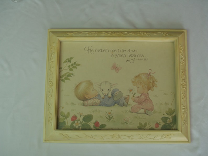 May include: A framed print with a yellow frame and a white mat. The print features a watercolor illustration of two children with a lamb. The text on the print reads "He maketh me to lie down in green pastures." - Psalm 23:2.