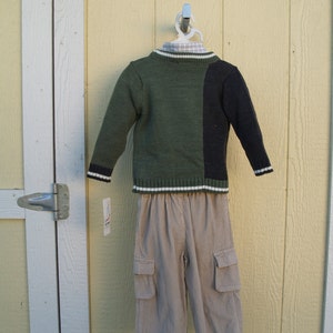 May include: A green and black sweater with a white stripe and a pair of beige corduroy pants with cargo pockets.