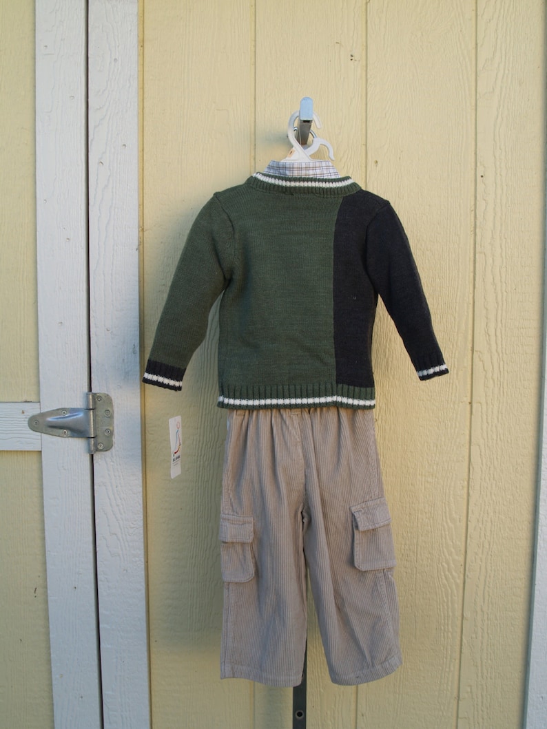 May include: A green and black sweater with a white stripe and a pair of beige corduroy pants with cargo pockets.