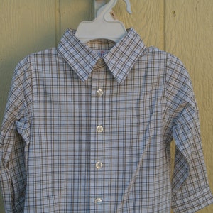 May include: A white long-sleeved button-down shirt with a brown and white plaid pattern.