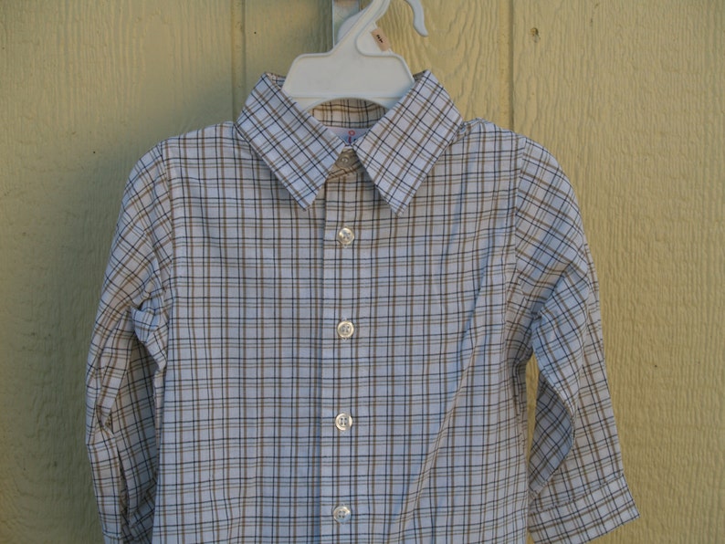 May include: A white long-sleeved button-down shirt with a brown and white plaid pattern.