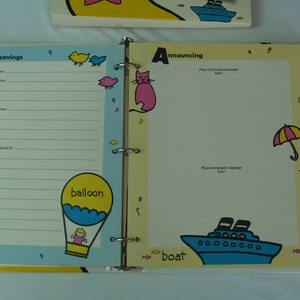 May include: A yellow binder with a blue and white boat on the cover. The binder has a section for "small savings" with a place to record savings bond information. The other side of the binder has a section for "announcing" with a place to put birth announcements and newspaper clippings.
