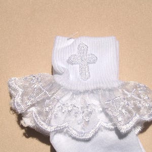 May include: White socks with a lace ruffle and a silver cross embroidered on the top.