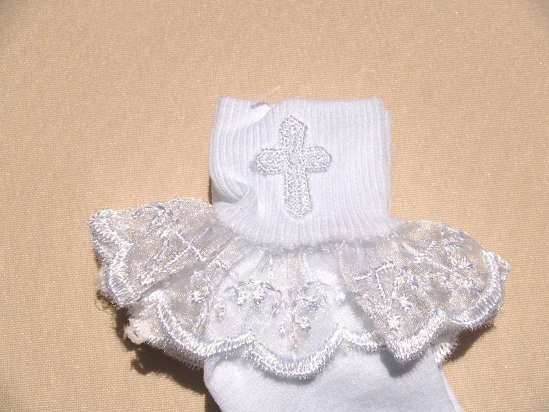 May include: White socks with a lace ruffle and a silver cross embroidered on the top.