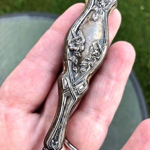 May include: An ornate, decorative knife with a floral design, silver-plated and with the word "Sterling" engraved on the handle.