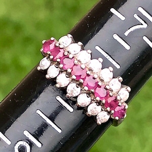 May include: A silver ring with a row of pink gemstones and a row of clear gemstones.