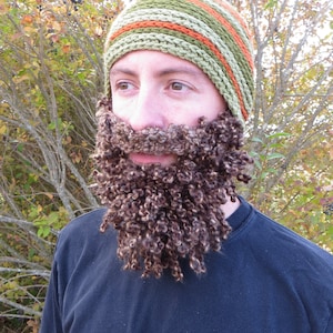 May include: A person wearing a green, orange, and brown striped crocheted hat with a brown crocheted beard.