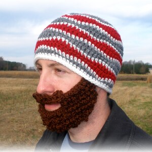 May include: A crocheted hat with red and gray stripes and a matching brown crocheted beard.