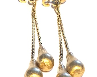 May include: Gold tone dangle earrings with three teardrop shaped charms on each earring. The earrings have a chain link design.