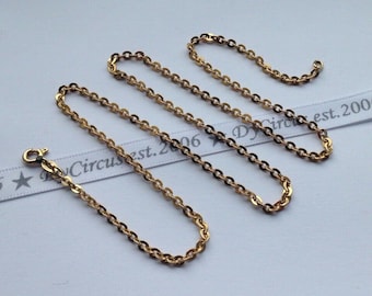 May include: A gold chain necklace with a lobster clasp. The chain is made of small, oval-shaped links.