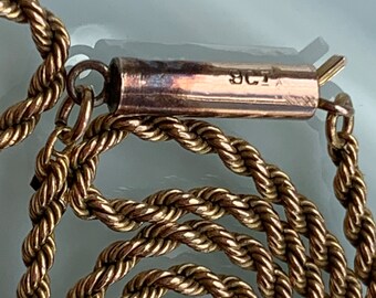 May include: A gold rope chain necklace with a clasp that has the inscription "8CT" on it.