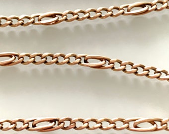 May include: Close-up of a gold chain with a curb link pattern. The chain is made of small, oval-shaped links that are connected by a series of smaller, round links.