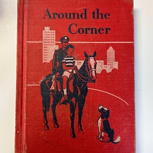 May include: Vintage book titled "Around the Corner" with a red cover. The cover features a black and white illustration of a police officer and a child on a horse, with a dog and city skyline. The book has visible wear.