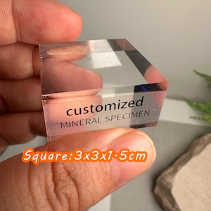 Puede incluir: Un esp&eacute;cimen mineral transparente y cuadrado con el texto "customized MINERAL SPECIMEN". Mide 3x3x1,5 cm. El esp&eacute;cimen se sostiene entre los dedos. Tambi&eacute;n se ve el texto "Square: 3x3x1.5cm".
