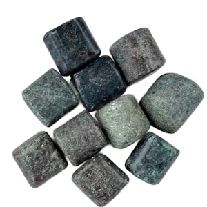 May include: A collection of dark green, square-shaped stones with rounded edges. The stones have a textured surface and varying shades of green and gray. The arrangement is scattered against a white background.